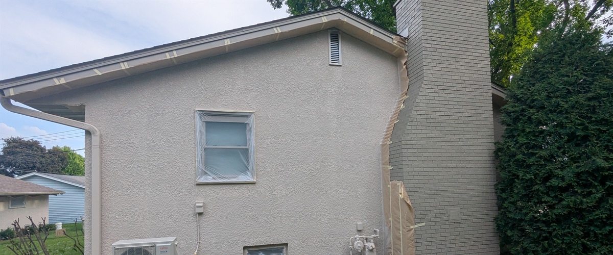 Rear stucco house painting project with repainted chimney in Osseo, MN