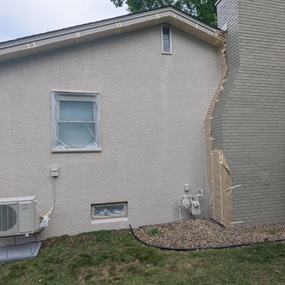 Rear stucco house painting project with repainted chimney in Osseo, MN